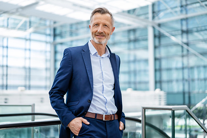 Mann hält sich an einem Geländer fest und blickt von einer Plattform in die Ferne.