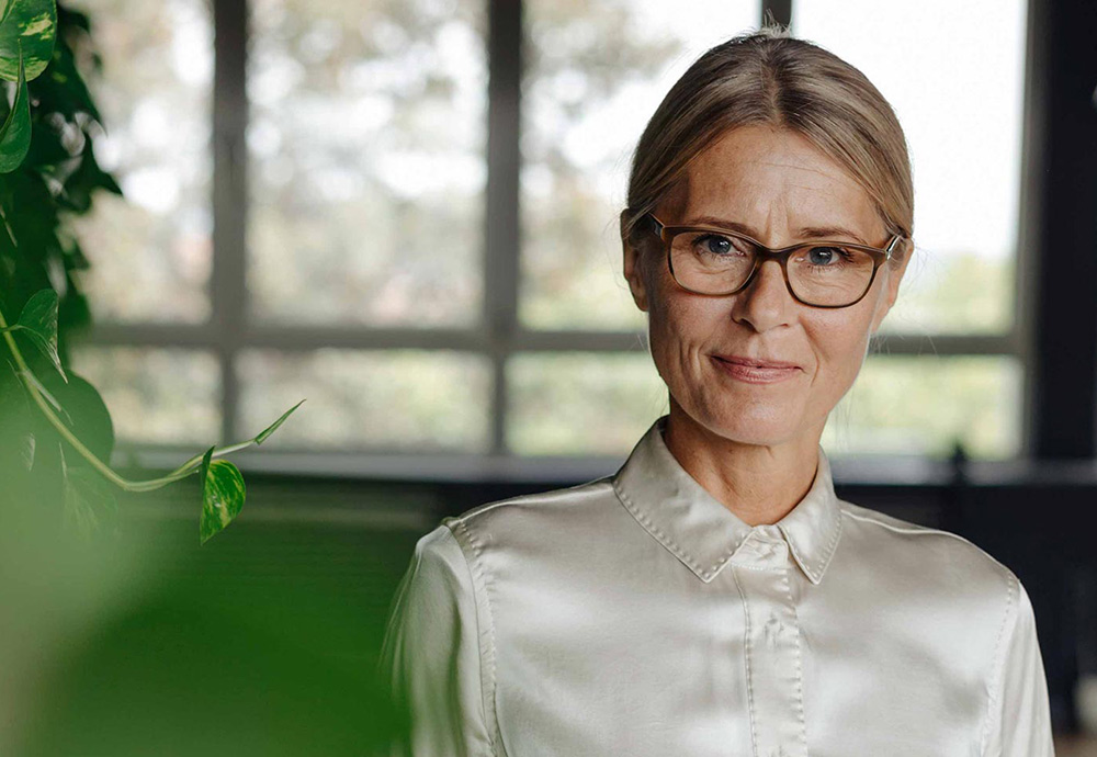 Frau mittleren Alters mit Brille schaut zielgerichtet in die Kamera.