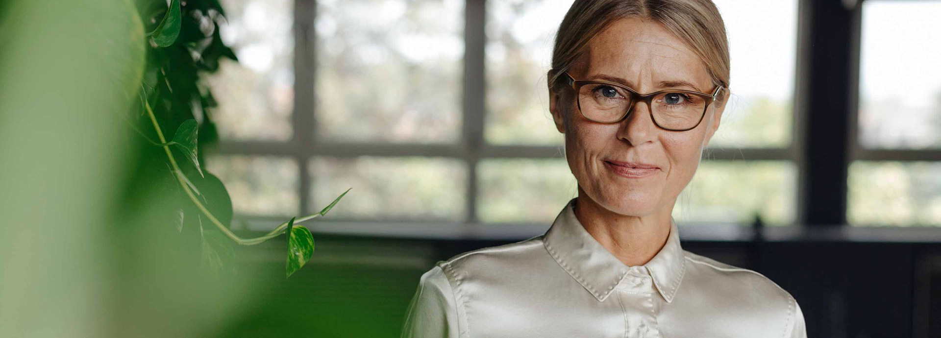 Frau mittleren Alters mit Brille schaut zielgerichtet in die Kamera.