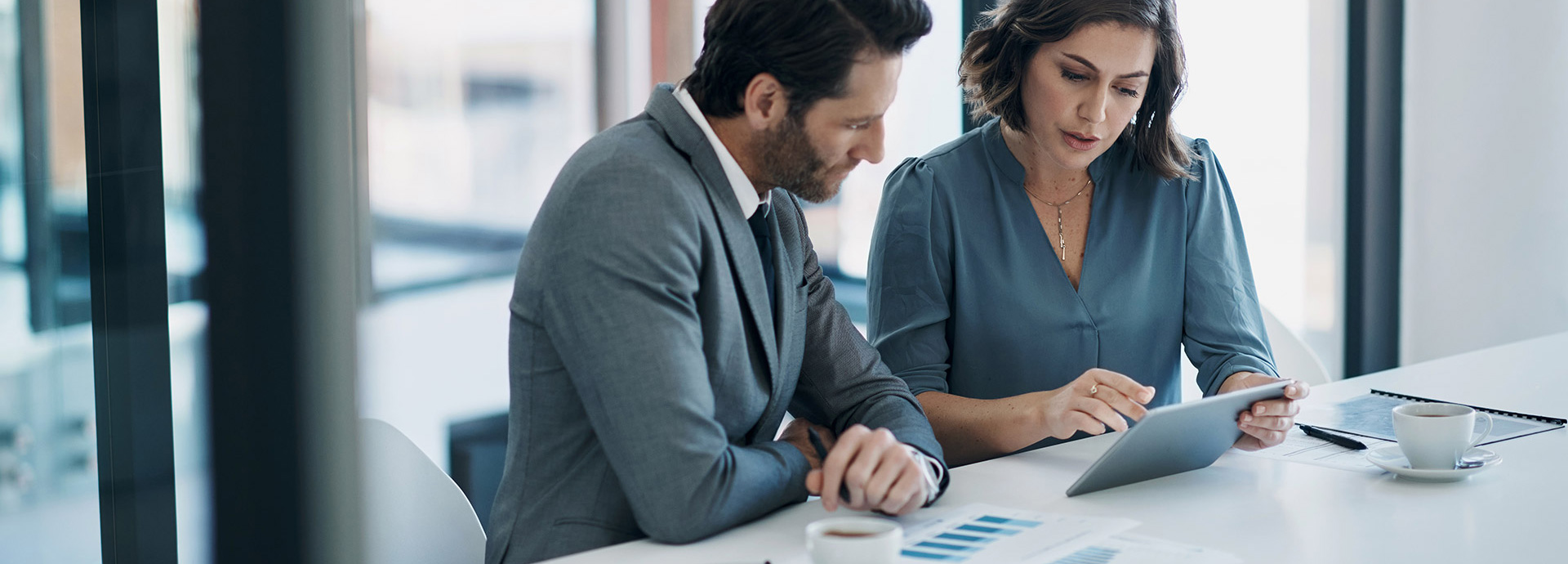 Mann und Frau in schicker Kleidung sitzen an einem Tisch und sprechen im Büro über Investor Relations.